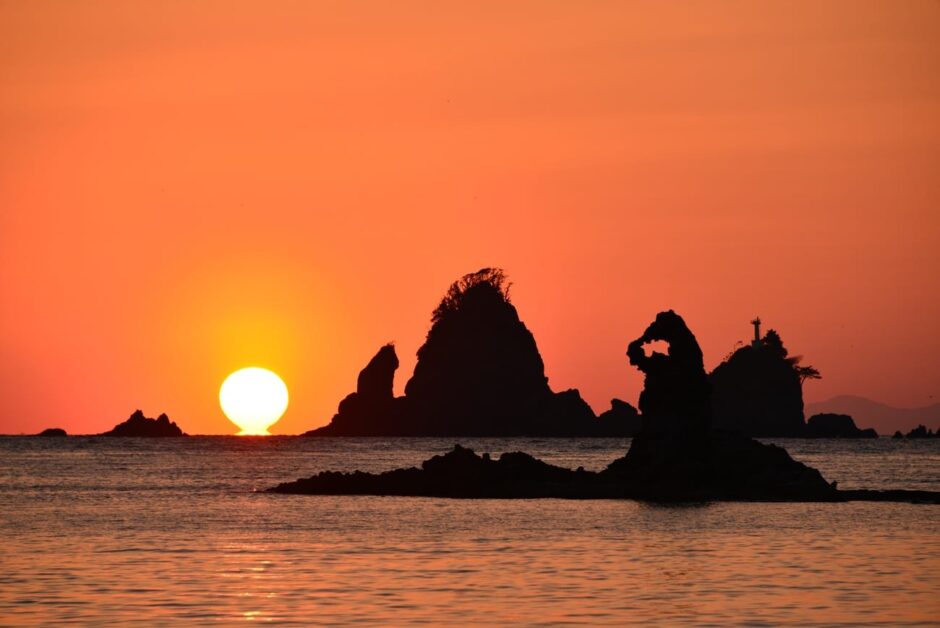 ゴジラ岩と夕陽（秋田県）